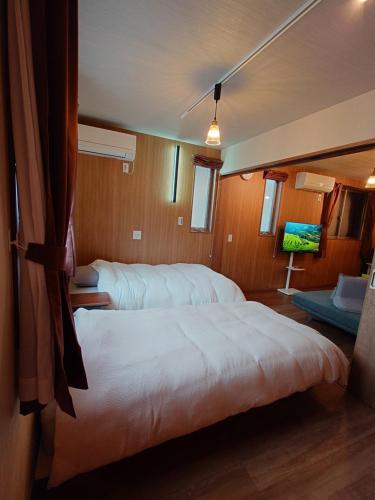 a bedroom with two beds and a tv in it at Lumen豊田 中長期滞在向コンドミニアム トヨタ自動車本社徒歩5分 in Toyota