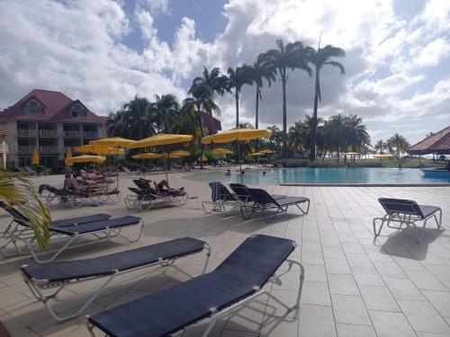 a resort with a pool with chairs and umbrellas at la Désirade in Sainte-Luce