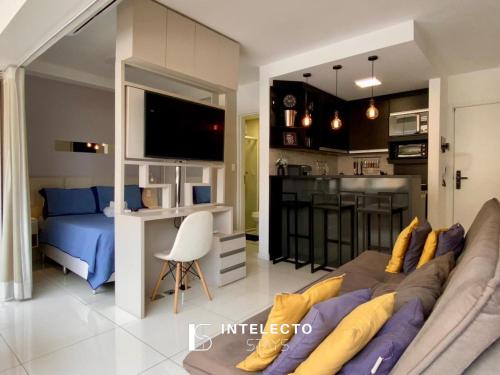 a living room with a couch and a tv and a kitchen at Living in Poços de Caldas