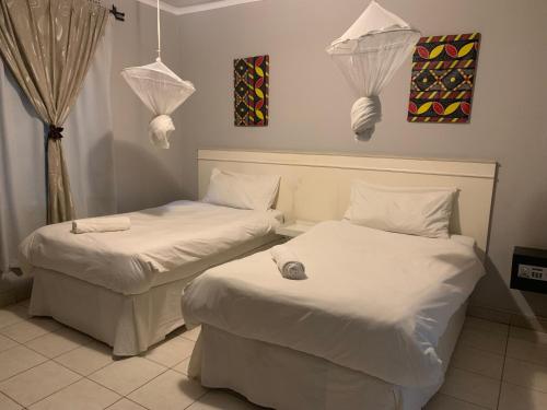 two beds in a room with white sheets at LePatino BnB in Livingstone