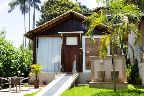 a house with a palm tree in front of it at Pousada Reserva Penedo in Penedo