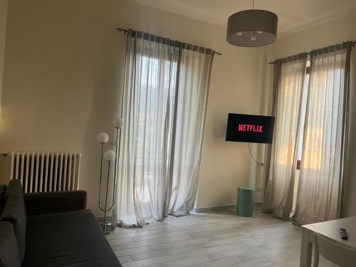 レッコにあるVilla Augusta Lecco Lake Comoのリビングルーム(白いカーテン、テレビ付)