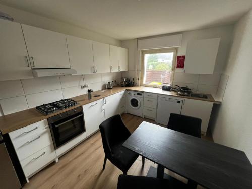 a kitchen with white cabinets and a table with chairs at Zimmer direkt an dem Rheinsteig neben der WHU mitten im Zentrum von Vallendar in Vallendar