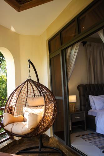 a room with a rattan chair and a bed at Manaya Luxury Diani Beach Serviced 2Bedroom with Pool & Parking in Galu