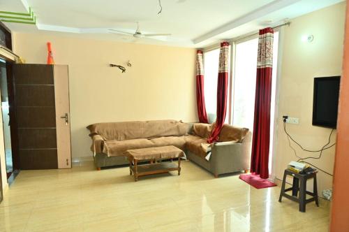 sala de estar con sofá y cortinas rojas en JD Homestays, en Jaipur