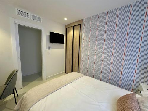 a bedroom with a bed and a tv on a wall at Picasso 2 Royale in Marbella