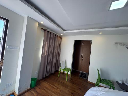 a bedroom with a bed and two green chairs at My Stay Nepal in Kathmandu