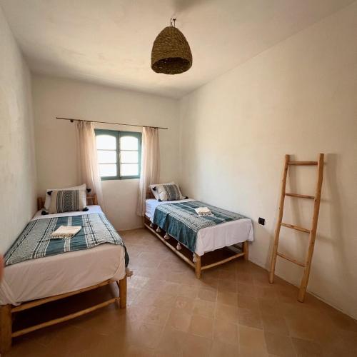 a bedroom with two beds and a ladder in it at Turquoise Brick Surf House in Sidi Kaouki