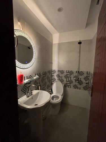 a bathroom with a sink and a toilet and a mirror at The little nest in Islamabad
