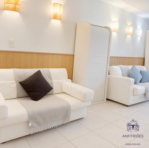 a living room with a white couch and a mirror at Anfitriões Angra- Flat com Vista Espetacular na Praia Grande in Angra dos Reis