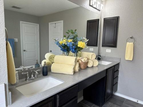 a bathroom with a sink and a vase of flowers on a counter at Relax with Spacious Modern Simplicity in Boerne