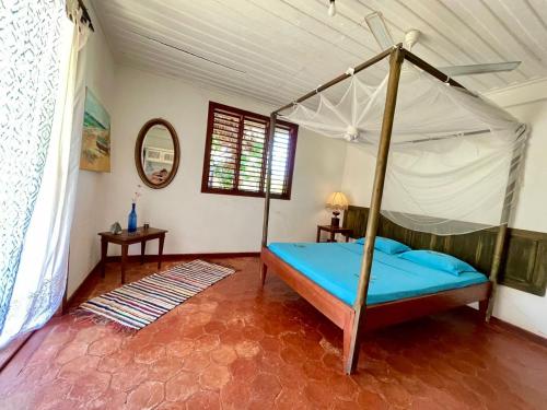 a bedroom with a canopy bed in a room at La Table d Alexandre Gîte de charme entre mangrove et mer in Hell-Ville