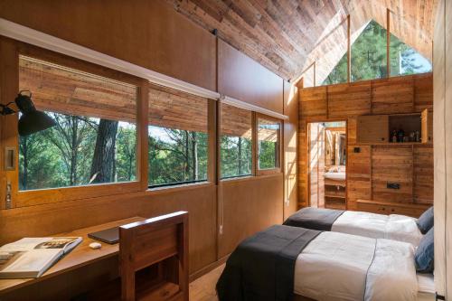 a bedroom with a bed and a desk and windows at Kaya Retreats - Diyathalawa in Ellealutwela