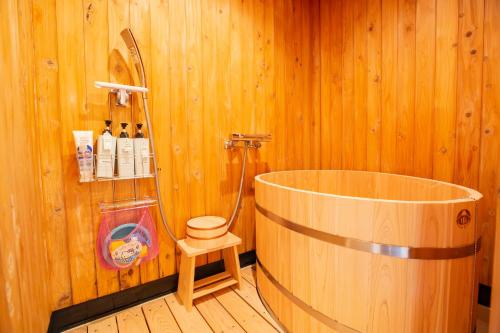 a wooden bathroom with a tub and a shower at HOJO MACHI HOSTEL in Kasai