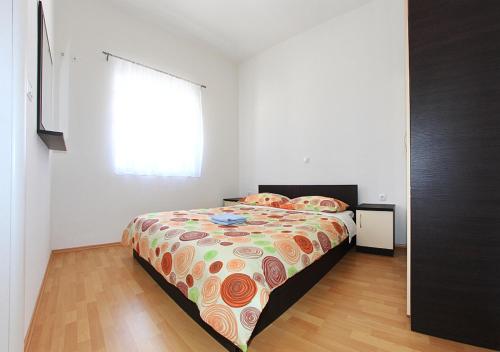 a bedroom with a bed with a comforter and a window at Apartment Stipan in Bibinje