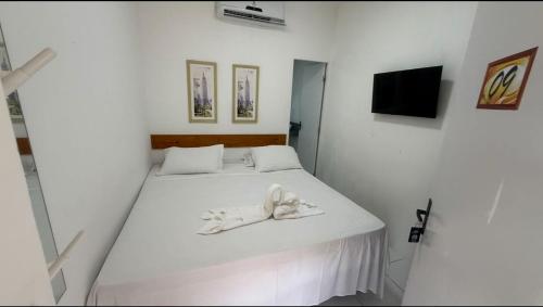 a white bedroom with a bed with a towel on it at Pousada Mel in Praia do Forte