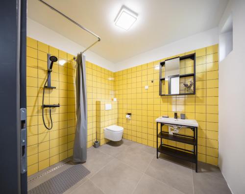 y baño amarillo con ducha y lavamanos. en Hypha etc, en Cîmpu Cetăţii