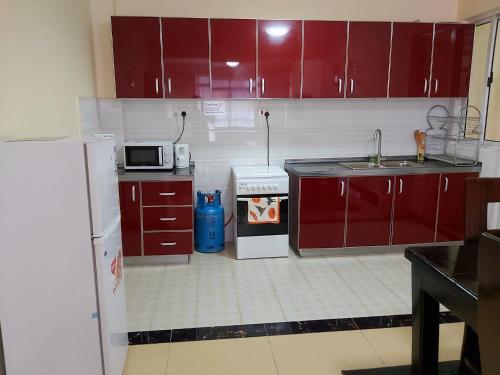 a kitchen with red cabinets and a sink and a microwave at Mango Court in Nairobi