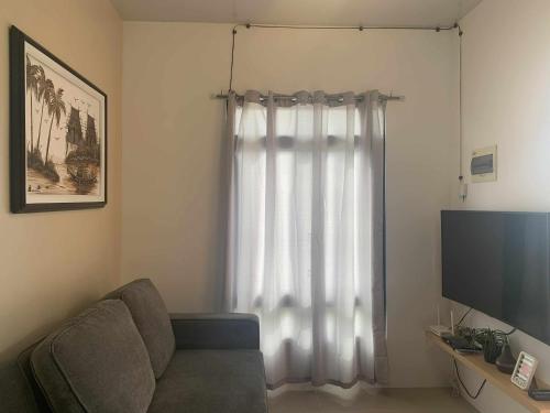 een woonkamer met een bank en een televisie bij Whole Furnished House with Parking and Sea View in Tagibo