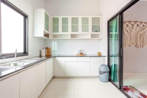 a kitchen with white cabinets and a sink and a window at 派对家园-11卧室独栋大泳池私密别墅 in Ban Huai Yai