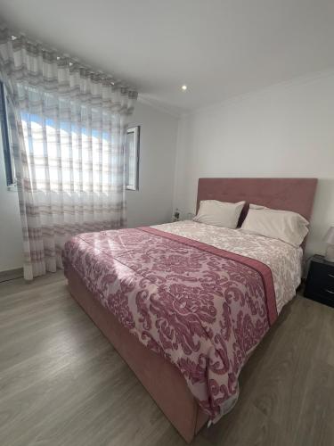 a bedroom with a bed with a purple blanket and a window at A Casa da Azenha in Sertã
