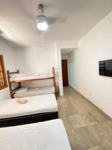 a room with two beds and a flat screen tv at Beach Milionario in Guarujá