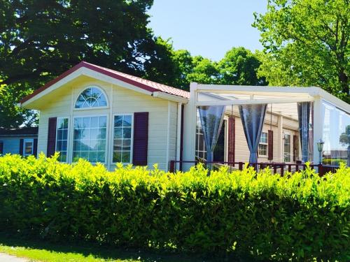 a small house with a pergola next to a hedge at Chalet-Urlaubsglück am See in Lathum
