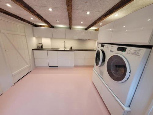a kitchen with a washing machine in a white kitchen at Villa Fuga kælderlejlighed in Jelling