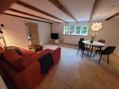 un salon avec un canapé rouge et une table dans l'établissement Villa Fuga kælderlejlighed, à Jelling