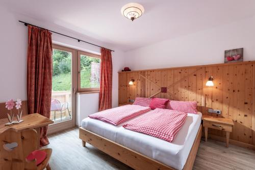 a bedroom with a bed and a desk and a window at Pension Mirabelle in Ellmau