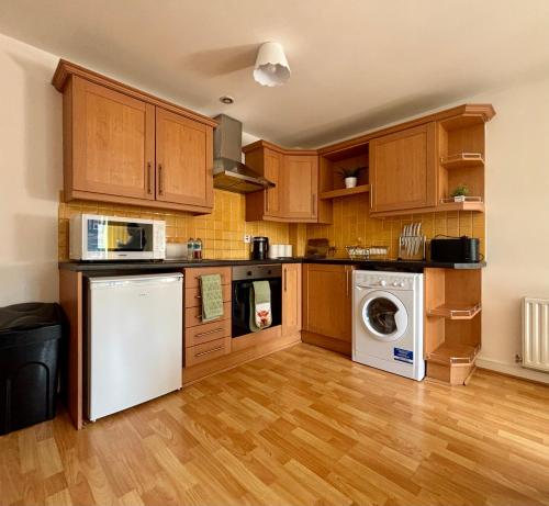 a kitchen with wooden cabinets and a washer and dryer at Stylish City Centre Stay with balcony - Near Football Stadiums in Liverpool