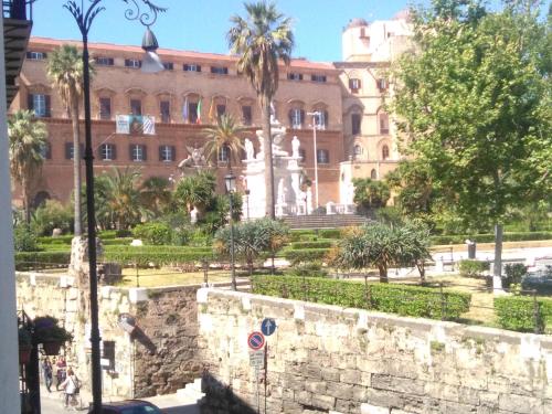 a building with a fountain and palm trees in front of it at Casa Normanna in Palermo