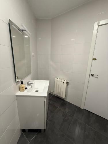 Un baño blanco con lavabo y espejo. en Petithouse Madrid Camino Viejo, en Madrid