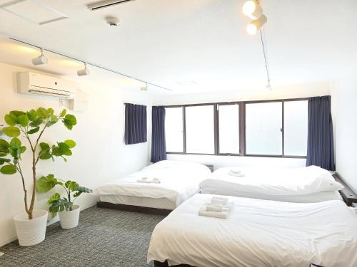 a bedroom with two beds and a potted plant at 2025年10月リニューアル! SLEEPLAB駒込-Komagome- in Tokyo