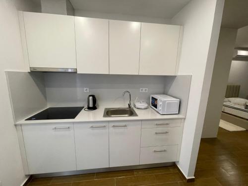 a kitchen with white cabinets and a sink and a microwave at Mix Center in Belas