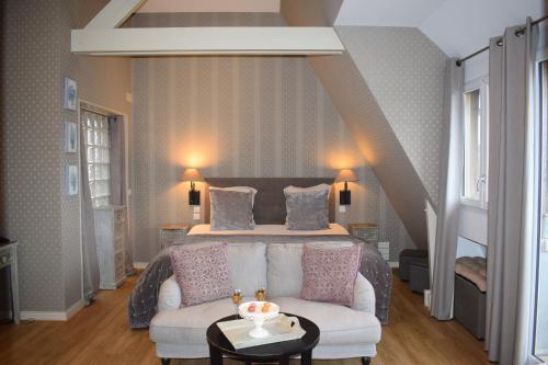 a living room with a bed and a white couch at Le Trophée Boutique Hôtel Spa- La Loggia Appart'hôtel in Deauville