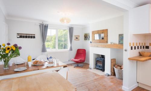 a living room with a table and a red chair at Spacious 3 Bed Cottage Near Beaches in Georgeham