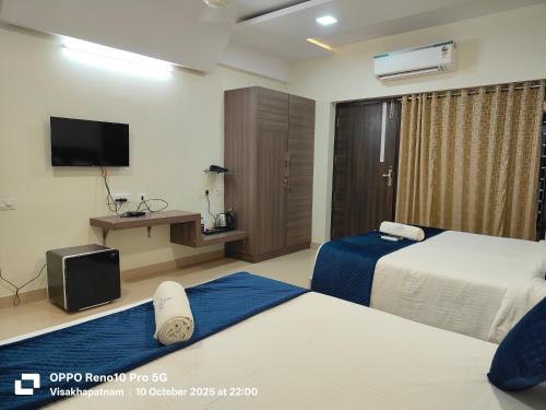 a hotel room with two beds and a flat screen tv at Hotel Vilaari Blue Marina in Visakhapatnam