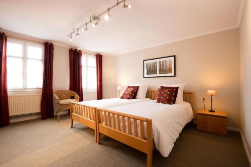 a bedroom with a bed and a chair and windows at Logis Hôtel Restaurant du Moulin in Ligneuville