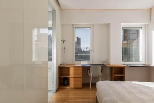 a bedroom with a desk and a bed and windows at Wonderful apartment a few steps from the Duomo - Milan in Costermano sul Garda