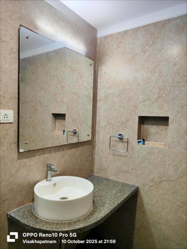 a bathroom with a sink and a large mirror at Hotel Vilaari Blue Marina in Visakhapatnam