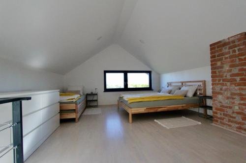 een zolderslaapkamer met twee bedden en een raam bij Kuća za odmor MIRINA in Aljmaš