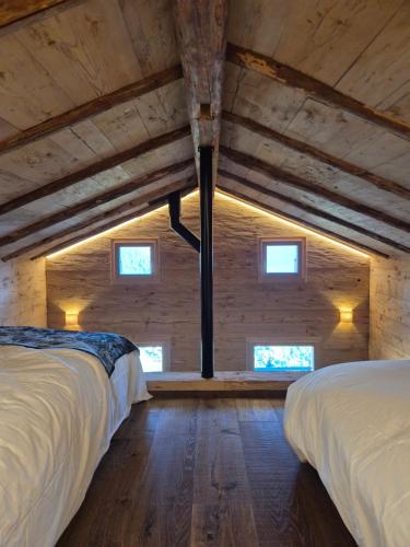 2 Betten in einem Zimmer mit Holzdecken und Fenstern in der Unterkunft Le Raidillon Verbier in Verbier