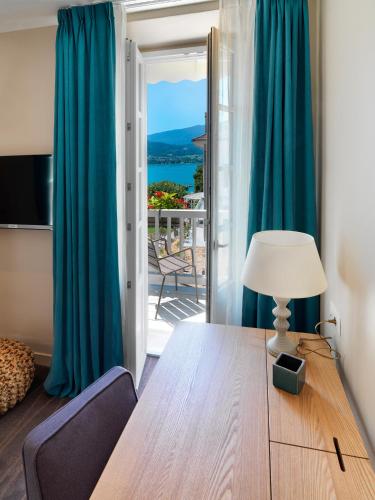 a room with a table with a lamp and a balcony at Hôtel Beau Site Talloires B SPA in Talloires