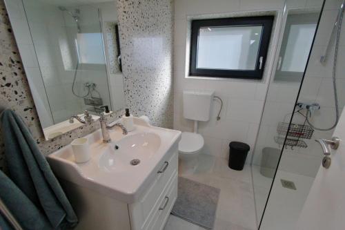 een witte badkamer met een wastafel en een douche bij Kuća za odmor MIRINA in Aljmaš