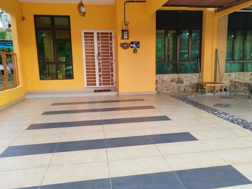 a house with yellow walls and a tiled floor at Afwan homestay klebang melaka in Melaka