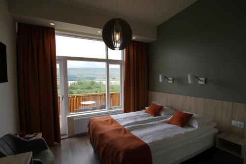 a bedroom with a bed and a large window at Hotel Hallormsstadur in Hallormsstaður