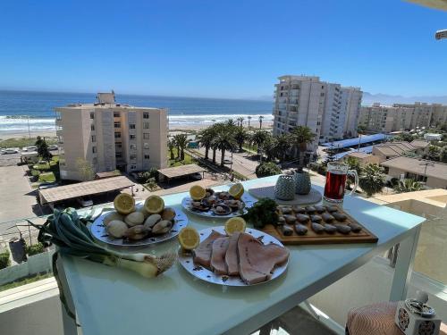 a table with two plates of food and the beach at Excelente departamento a 150 metros de la playa en La Serena in La Serena
