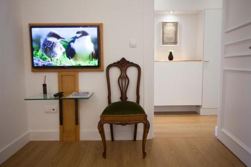 a room with a chair and a television on a wall at Otília Apartamentos in Lisbon
