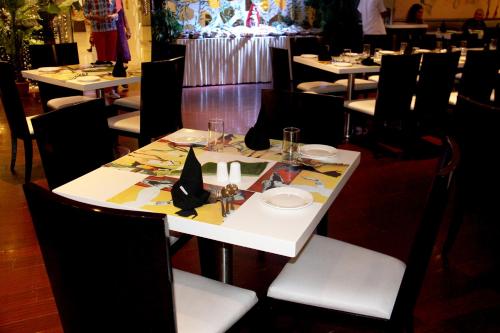 a table in a restaurant with a white table with chairs at The Fern Residency Rajkot in Rajkot